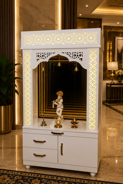A white wooden Shiva mandir altar cabinet with gold accents, illuminated by warm yellow LED lights, set in a luxurious indoor lobby with marble floors and gold-toned columns.