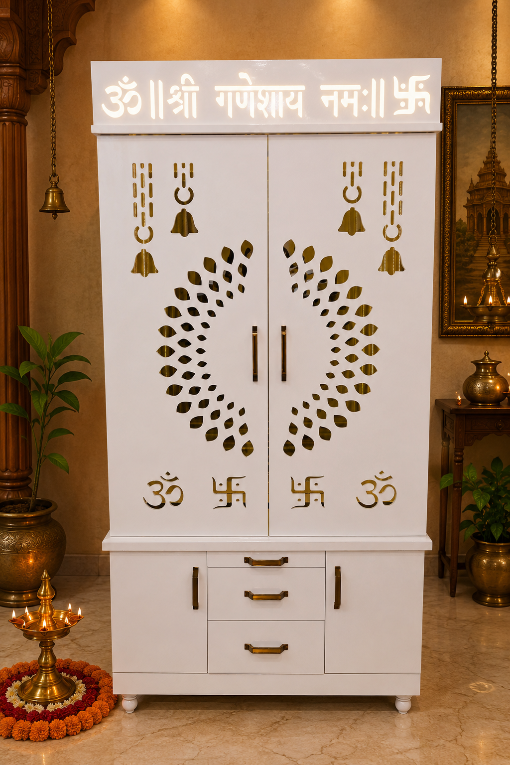 A white wooden Shree Ganeshay Namah altar cabinet with gold decorative carvings, bell motifs, and Sanskrit mantras, set in a warm, traditional Indian room.