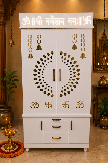 A white wooden Shree Ganeshay Namah altar cabinet with gold decorative carvings, bell motifs, and Sanskrit mantras, set in a warm, traditional Indian room.